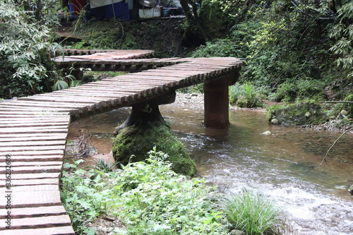  wooden bridge pathway a river in a mountain forest in Sichuan, China