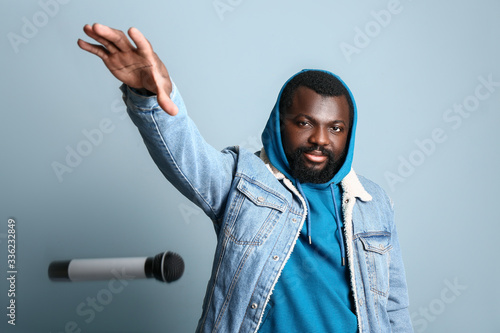 Valokuva Male African-American singer dropping microphone on color background