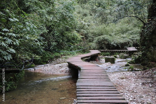  wooden bridge pathway a river in a mountain forest in Sichuan, China