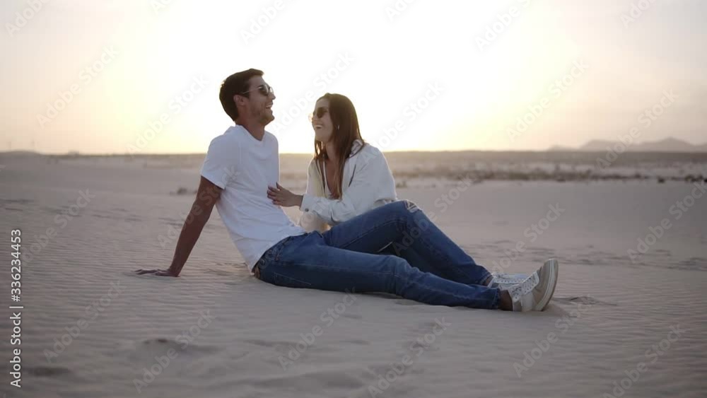 Young man and woman sitting in desert beautiful couple girl and guy sand dune landscape background. Mild dusk. Romantic couple having time together Young man and woman sitting in desert beautiful couple girl and guy sand dune landscape background. Mild dusk. Romantic couple having time together