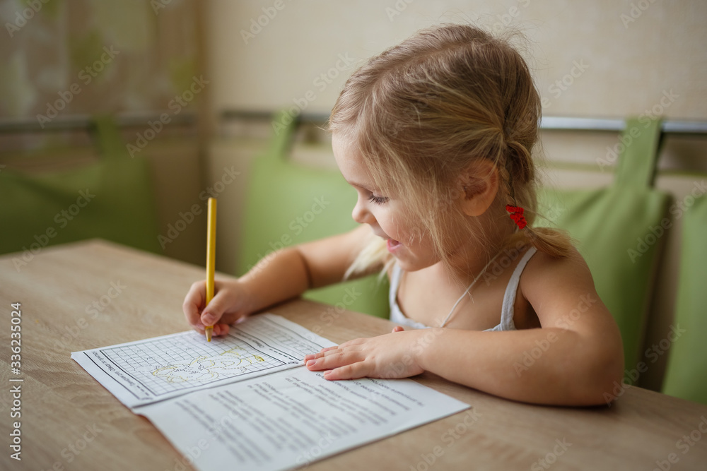 girl writes at the table at home, studies, holidays, quarantine, children at home girl writes at the table at home, studies, holidays, quarantine, children at home