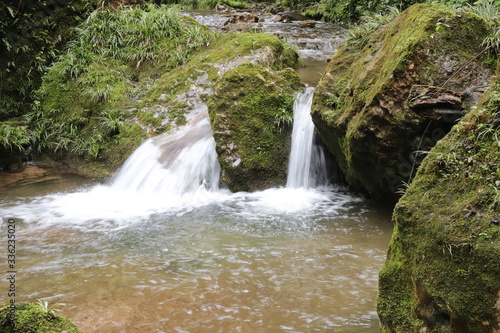 Beautiful landscape of cascade falls over mossy rocks, stones cover with moss, in a Mountain in Sichuan, China