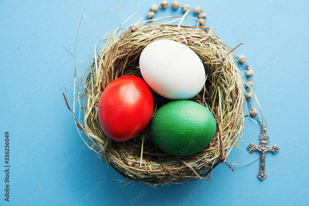 Wishes for Happy Easter holiday card in Italian, Easter eggs as the color of the Italy flag in nest on blue Wishes for Happy Easter holiday card in Italian, Easter eggs as the color of the Italy flag in nest on blue