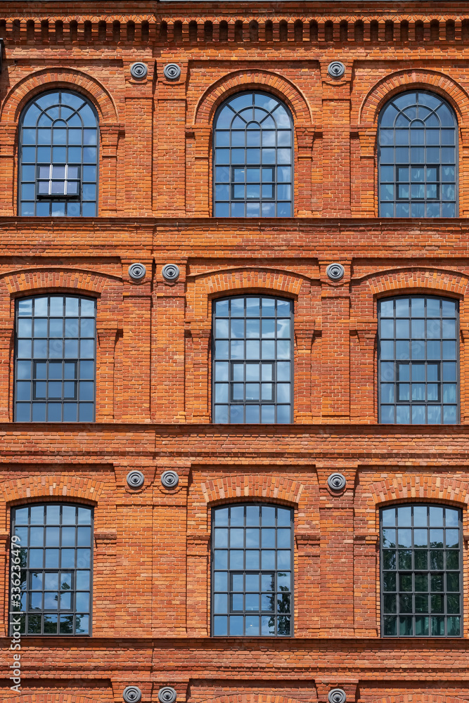 Red brick classic industrial building facade with multiple windows background.
