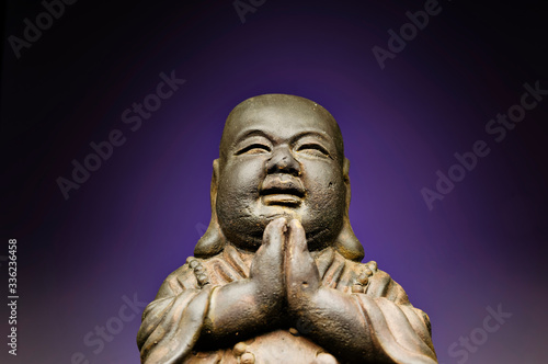 A small replica statue of The Buddha with a green background. Purple representing divinity and immortality