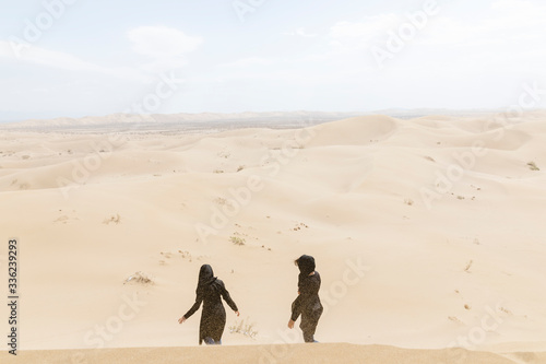 Two women walk on the dunes of the desert of Varzaneh photo