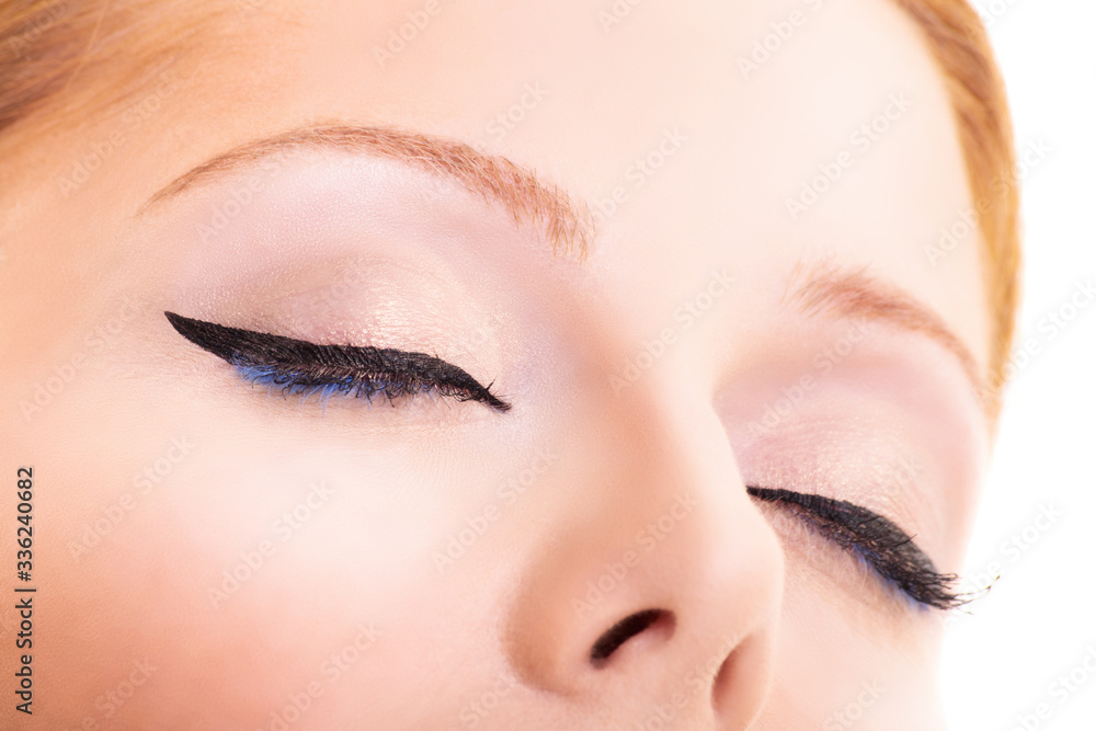 Close-up of closed eyes with black eyeliner and glowing clean skin