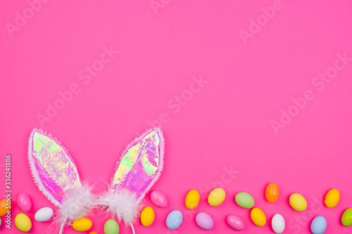  A lot of colored easter eggs  on a pink background. Bunny ears as a symbol of the spring holiday. Happy Easter card with copy space for text. Minimal style. Banner. Long format