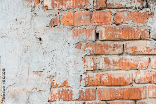 Texture of an old broken red brick wall with cement mortar. Background of red clay brick on a broken wall with cement mortar and plaster