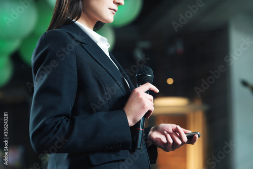 Business and speech topic: woman in a white shirt holding a black microphone, indoor