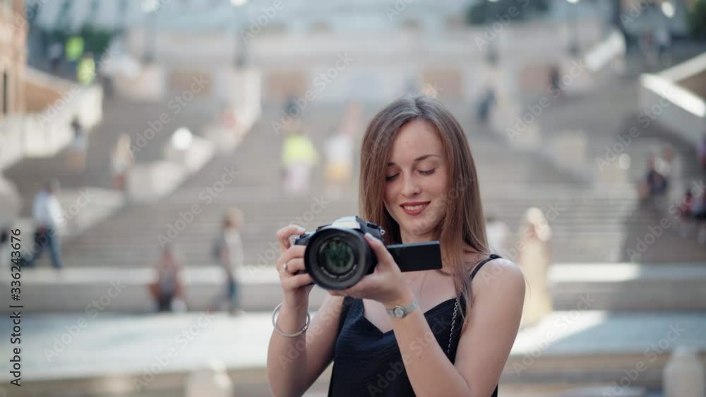 Pretty smiling girl with long brown hair exploring the world, travelling and taking pictures with black digital camera. Tourist female recording memories from journeys, girl taking pthotos and videos Pretty smiling girl with long brown hair exploring the world, travelling and taking pictures with black digital camera. Tourist female recording memories from journeys, girl taking pthotos and videos