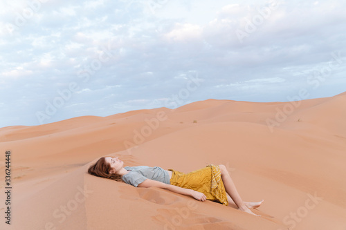 Young woman lying in sand dune in Sahara Desert, Merzouga, Morocco