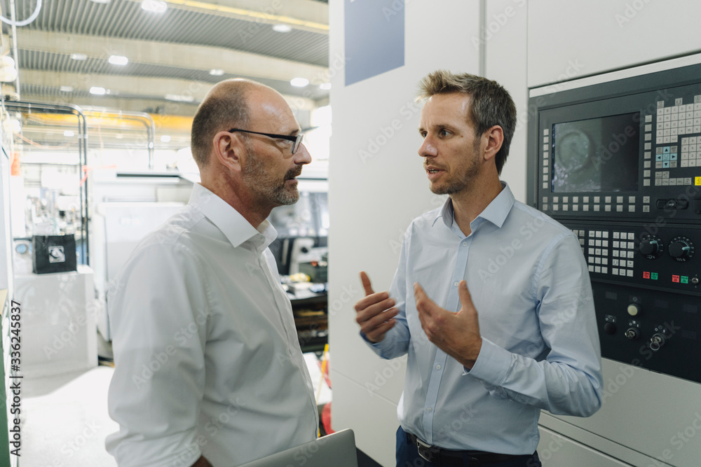 Two men talking in a factory Two men talking in a factory