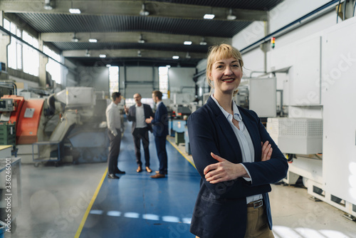 Portrait of a confident businesswoman in a factory with colleagues in backgound photo