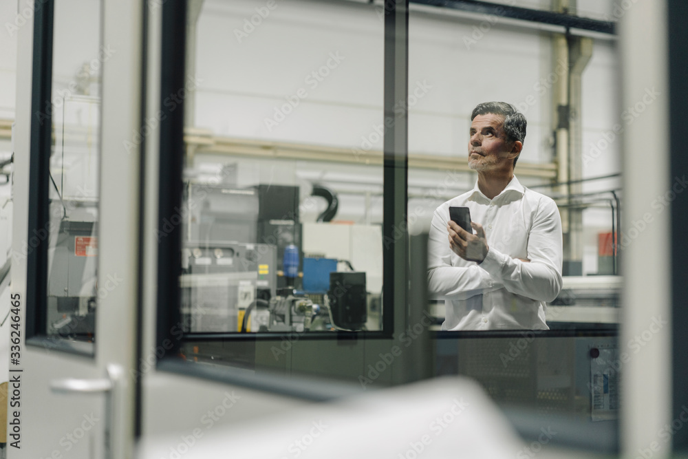 Mature businessman with cell phone in a factory Mature businessman with cell phone in a factory