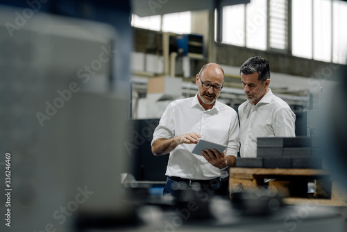 Two businessmen using tablet in a factory photo