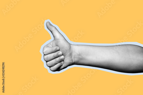 Child hand shows thumb up on yellow background. Paper cut style.