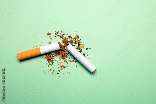Broken cigarette on a green background, tobacco