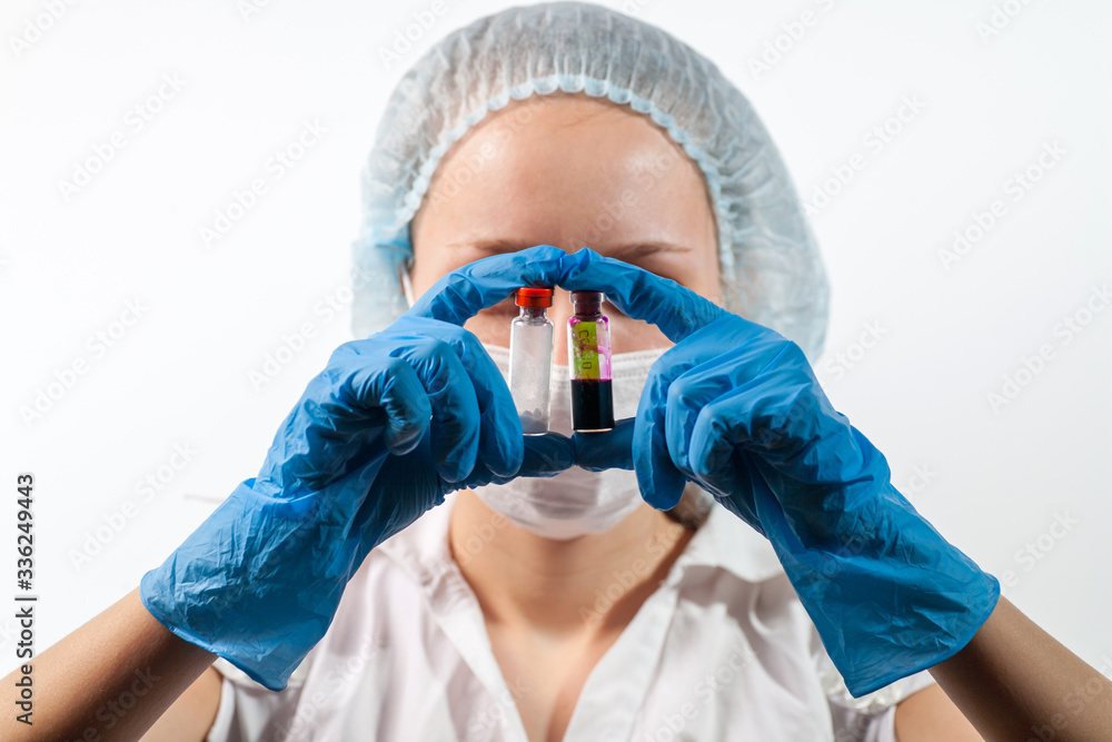 Fototapeta premium The doctor is wearing a respiratory mask with a positive blood test for a new rapidly spreading coronavirus SARS-CoV-2originating from Russia, Kommunarka. The doctor holds a test tube COVID-19