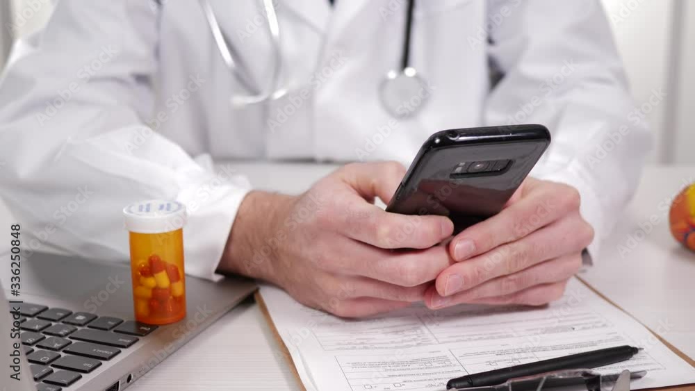 Medical Professional Doctor, using his mobile device in his office, typing in information, Medical Professional Doctor, using his mobile device in his office, typing in information,
