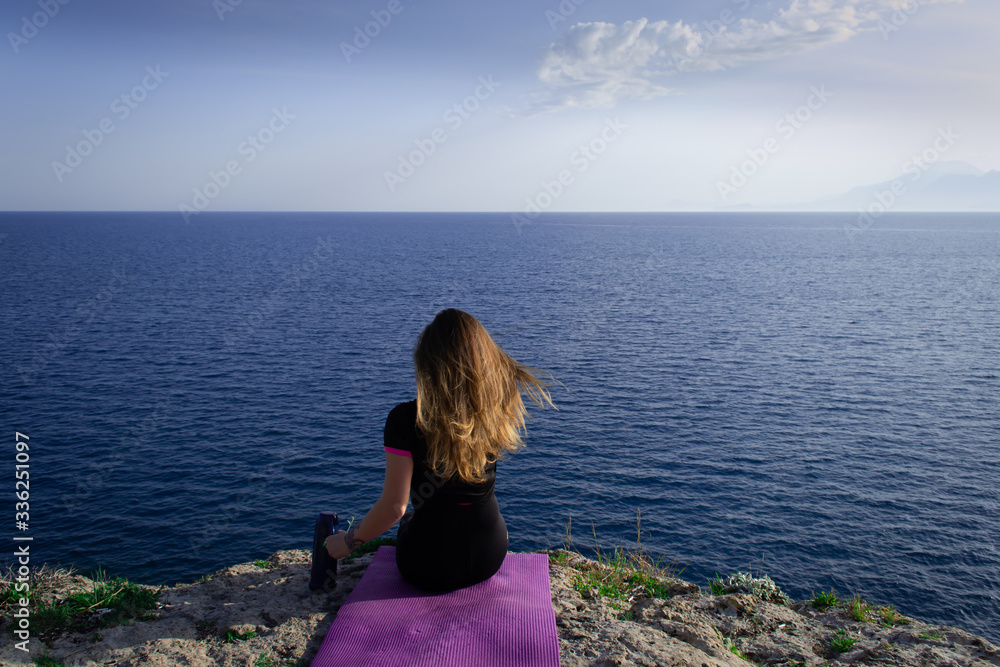 Beautiful young happy lonely girl watching the Mediterranean sea and relaxing