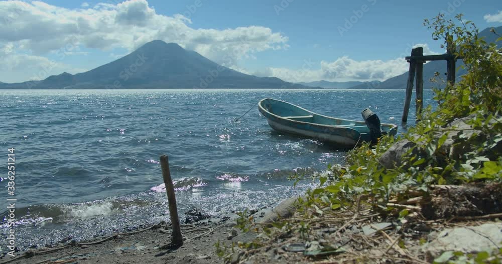 A small boat in a body of water with Lake Atitlan in the background A small boat in a body of water with Lake Atitlan in the background