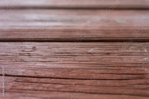 Wood grains showing through fading brown weathered paint on pitch pine boards