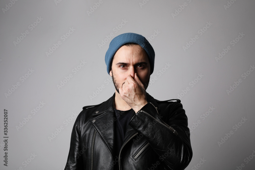 Young bearded hipster suffering of bad smell and posing on the white background. Vertical. Young bearded hipster suffering of bad smell and posing on the white background. Vertical.