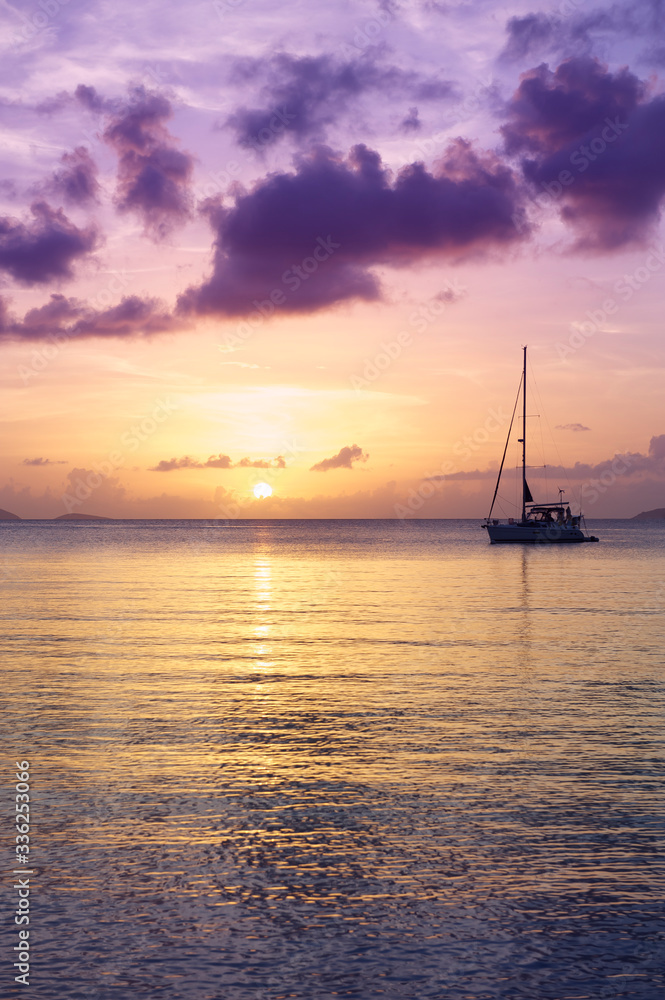 Scenic sunset with tropical purple clouds reflecting on calm Caribbean sea