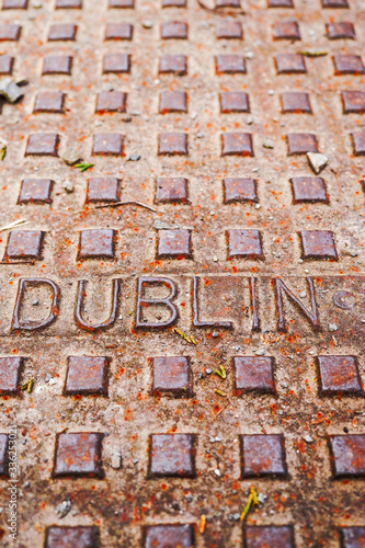 Dublin sign on a metal manhole, rusty weathered surface, selective focus.