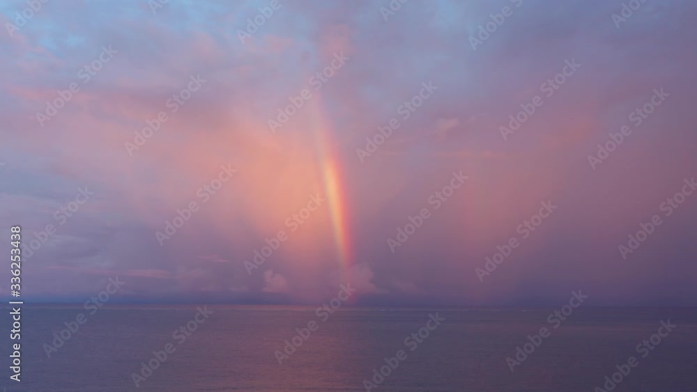 A stunning sight of a rainbow over the waves during sunrise - wide shot A stunning sight of a rainbow over the waves during sunrise - wide shot