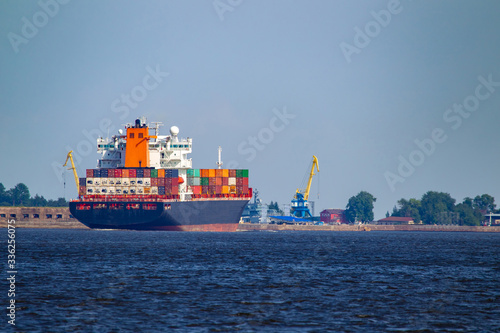 Cargo ships sailing off the coast. Container ship near the cargo port. Container ship on the background of blue sky. Shipping. Concept - Transfer of goods by water. Containers loaded on a sea vessel