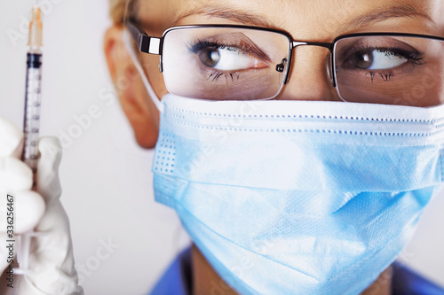 woman doctor in mask, female medical nurse or pharmacist with vaccine syringe