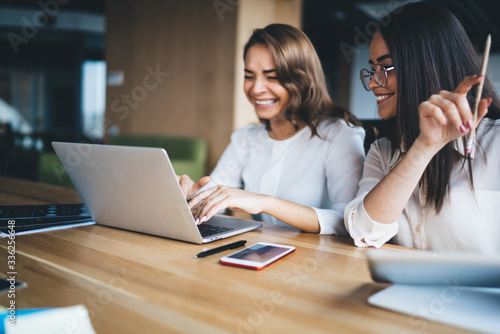 Cheerful ladies using laptop in office