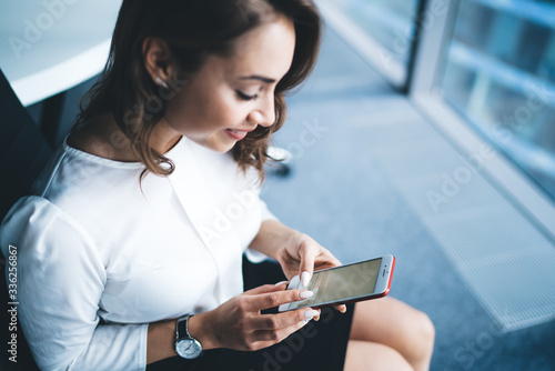 Modern happy female office worker using smartphone in office