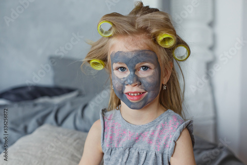 A little girl plays with a cosmetic SPA mask on her face. Little girl enjoying Spa treatments. SPA and Wellness.