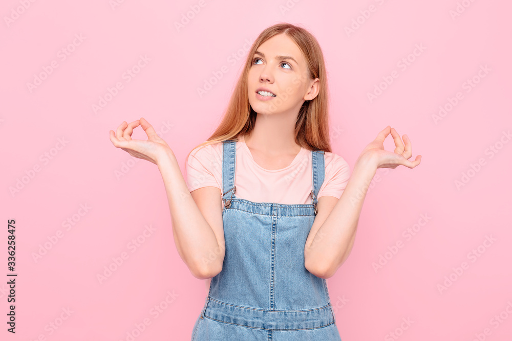 A calm , relaxed girl relieves stress by meditating with her arms outstretched, standing in a Lotus position on a pink background A calm , relaxed girl relieves stress by meditating with her arms outstretched, standing in a Lotus position on a pink background