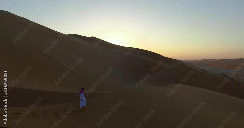 4K Drone Shot of Man Walking in Desert Sunset Over Sand Dunes in Dubai UAE Dressed in Traditional Clothes 4K Drone Shot of Man Walking in Desert Sunset Over Sand Dunes in Dubai UAE Dressed in Traditional Clothes