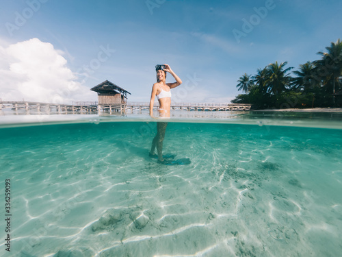 Caucasian traveller with snorkel mask feeling happiness and freedom during tropical vacations on Indonesian island with palm trees and crystal water for exploring ocean shallow, holidays on Raja Ampat