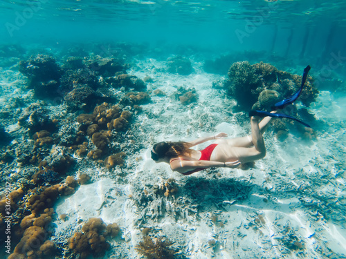 Young female snorkeling in sea near coral reef