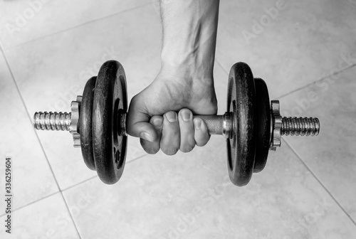 Closeup to male hand squeezing an old iron dumbell. Ideal for fitness, sports, healthy life, gym and home workout. 