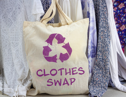 Obraz na plátně Clothes swap reusable bag with recycle textiles symbol in front of rack of clothes