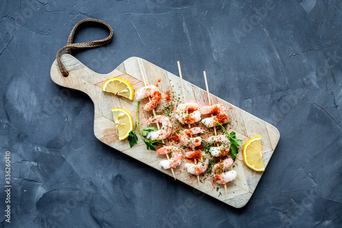 Shrimp skewers - seafood snack - on cutting bioard on grey table top view photo