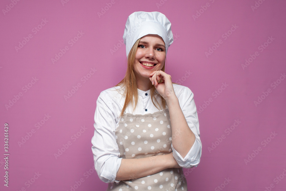 beautiful girl cook in uniform and apron on a colored pink background, portrait of a housewife woman in kitchen clothes beautiful girl cook in uniform and apron on a colored pink background, portrait of a housewife woman in kitchen clothes