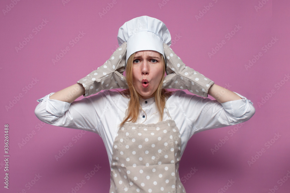 surprised girl cook in uniform, apron and gloves for baking screaming on a colored background, beautiful woman housewife in kitchen clothes hold hands to head