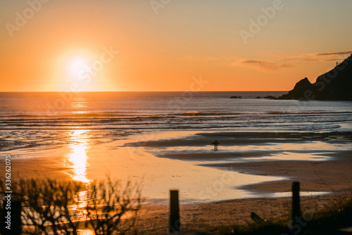 sunset on the beach with surfers walking