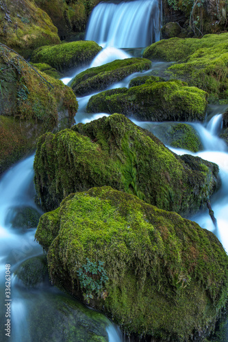 waterfall cascade over green moss rocks in the forest