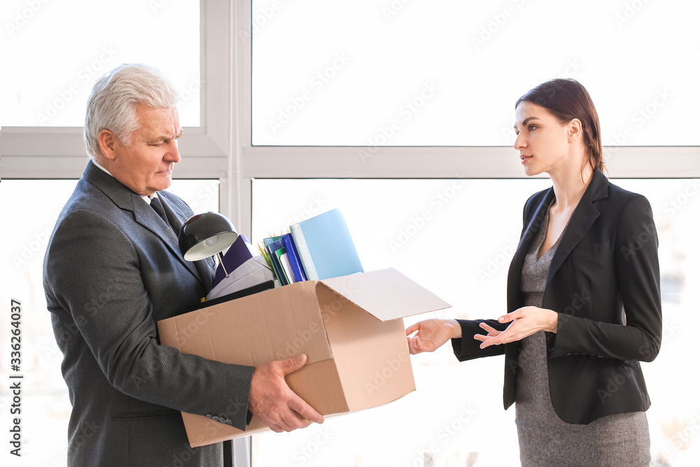 Woman calming her fired mature colleague in office Woman calming her fired mature colleague in office