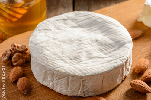 Closeup on a Camember cheese wheel and almonds on wooden background photo