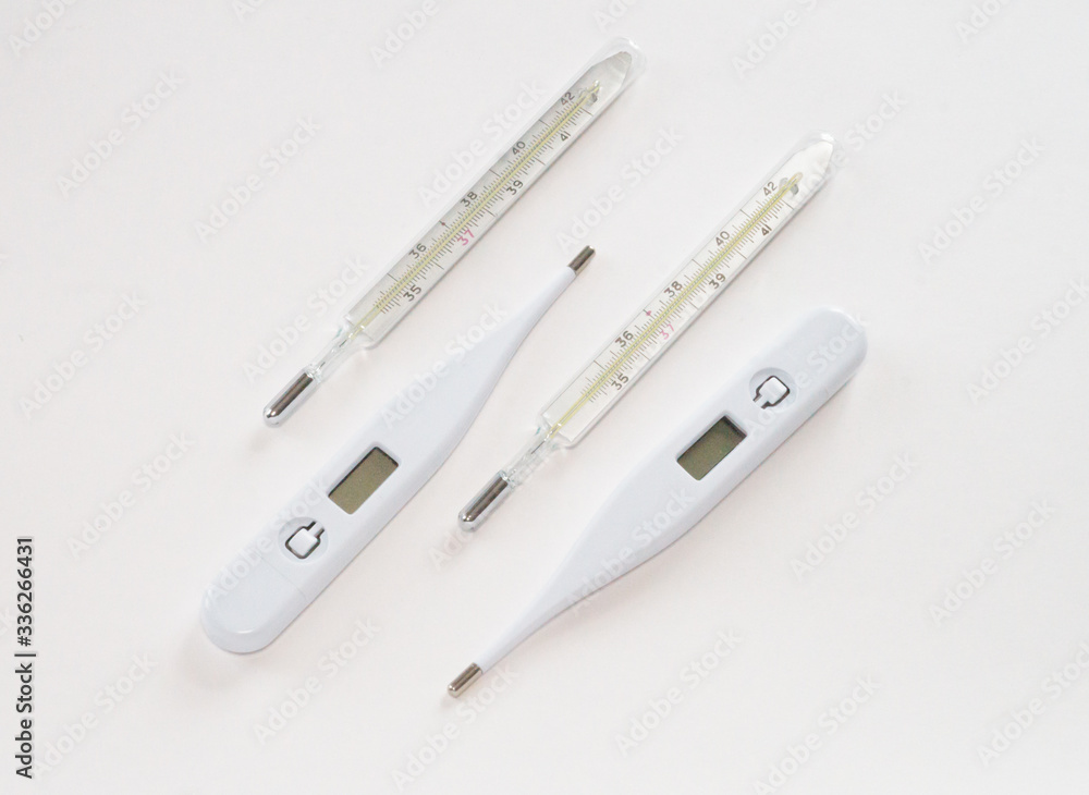 Two white electronic thermometers and two analog mercury thermometers on a white background Two white electronic thermometers and two analog mercury thermometers on a white background